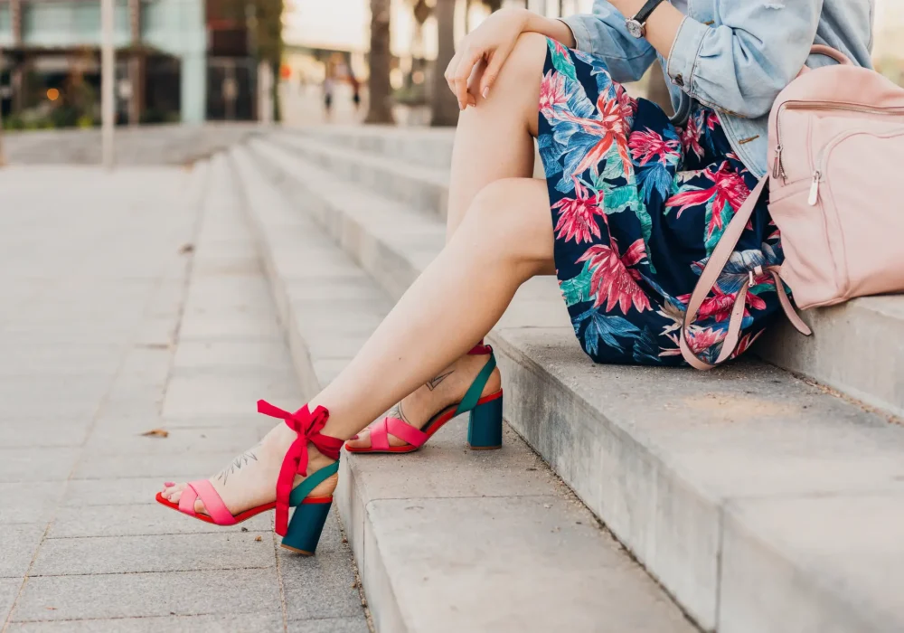 close-up-details-legs-pink-sandals-woman-sitting-stairs-city-street-stylish-printed-skirt-with-leather-backpack-summer-style-trend